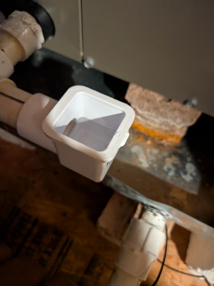 White condensate drain fitting installed at HVAC equipment