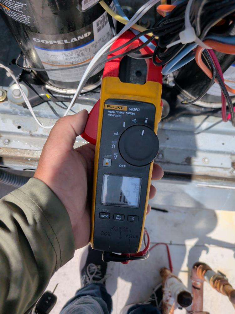 Technician testing rooftop HVAC electrical current in Austin