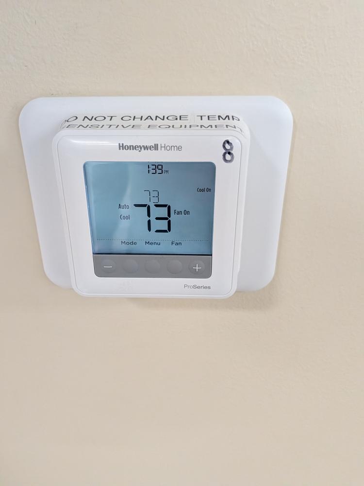Commercial office thermostat displaying 73 degrees