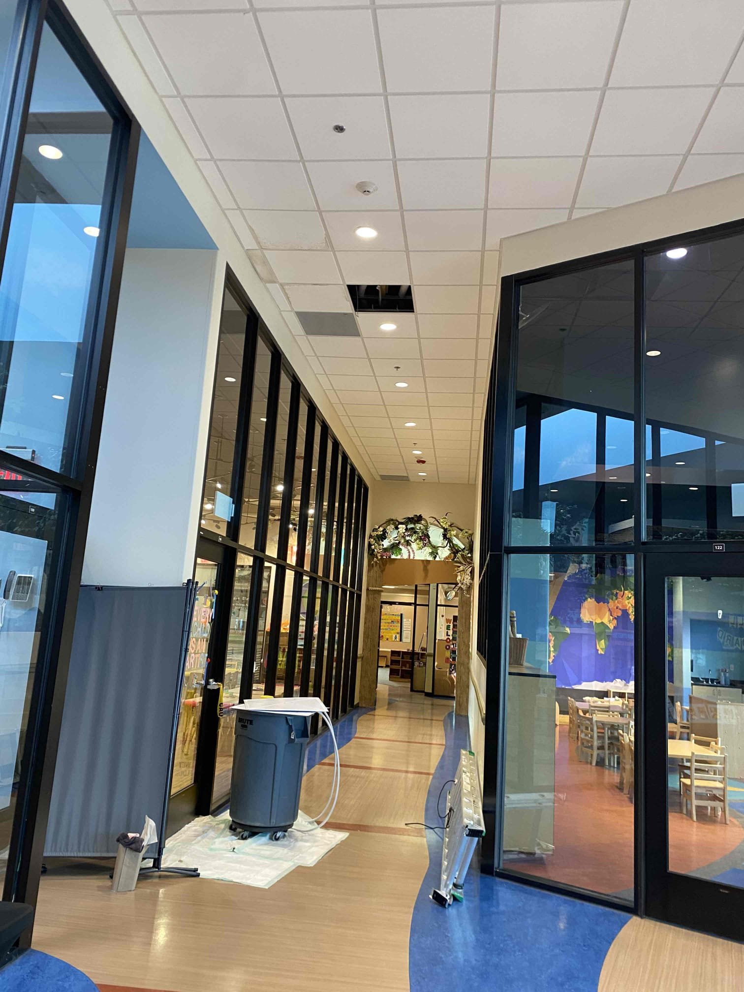 Commercial corridor with ceiling tiles removed for inspection