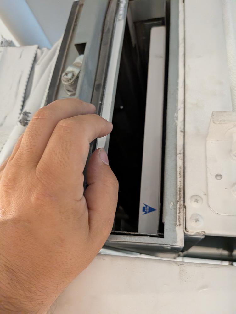 Technician accessing concealed Daikin filter compartment